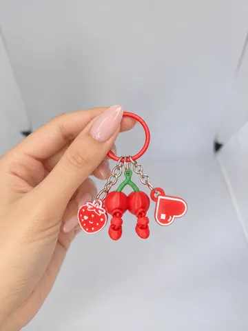 Llavero con charms de cerezas y corazones, en la mano