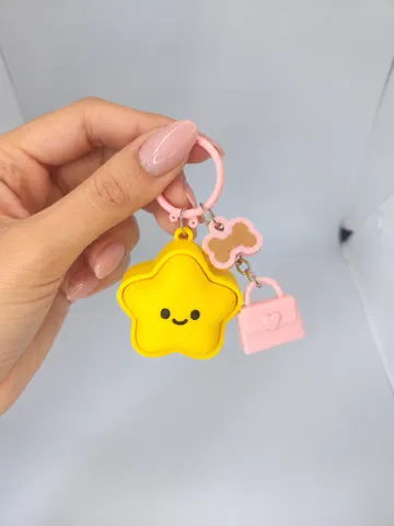 Llavero de estrella con charms de hueso y bolso, en la mano