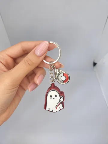 Llavero de fantasma con charm de pokébola, en la mano