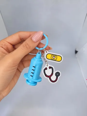 Llavero de jeringa con charms de curita y estetoscopio, en la mano