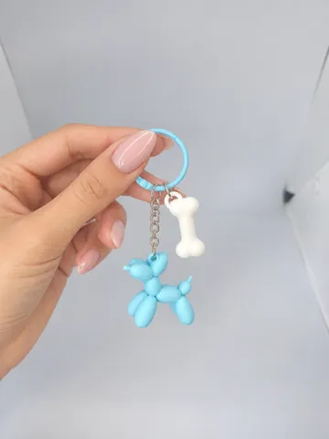 Llavero de perrito de globo con charm de hueso, en la mano
