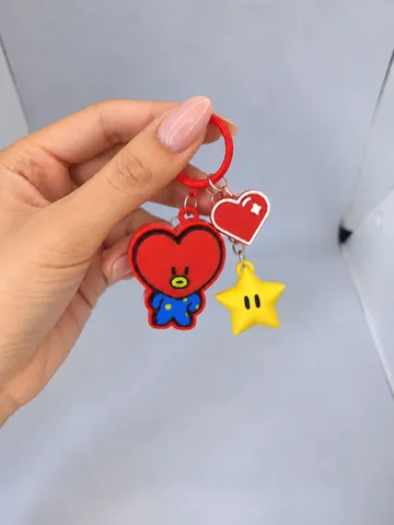 Llavero de Tata BT21 con charms de corazón y estrella, en la mano